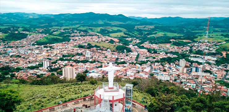 A vista panorâmica da cidade de Socorro-SP a partir do Mirante do Cristo, com suas ruas sinuosas e telhados vermelhos se estendendo até as montanhas que cercam a região.