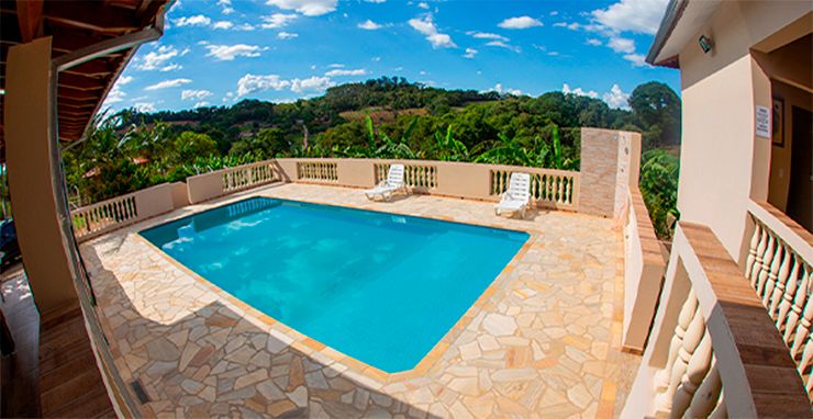 Piscina cristalina cercada por beleza natural e ambiente acolhedor. Renove suas energias e contemple a paisagem deslumbrante sob um céu azul radiante.